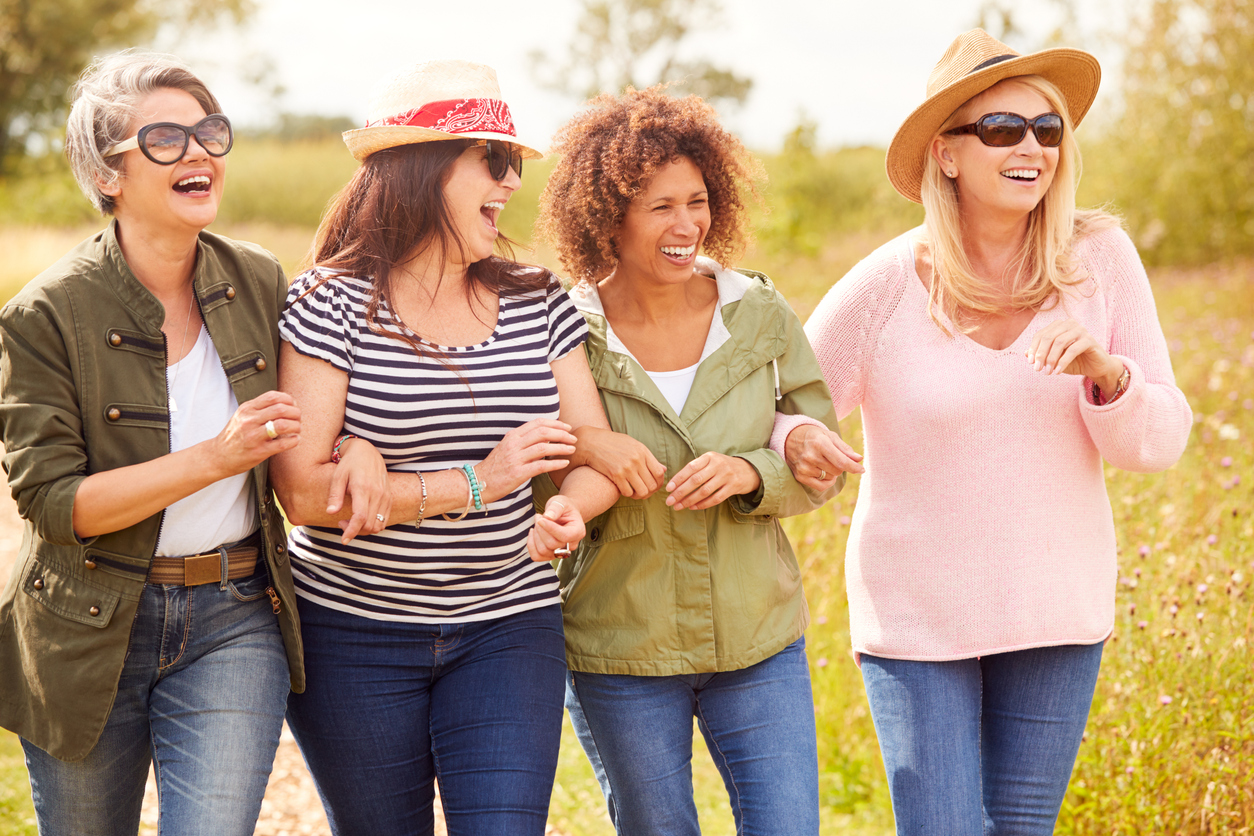 Group Of Mature Female Friends Walking Along Path Through Yurt Campsite Home
